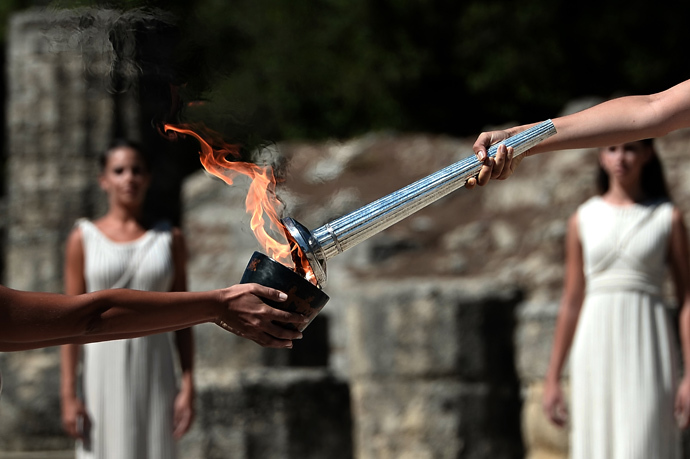 Greek actress Ino Menegaki (R) acting as the high priestess holds the Olympic Flame at the Temple of Hera on September 29, 2013 during the lighting ceremony in ancient Olympia (AFP Photo / Aris Messinis)