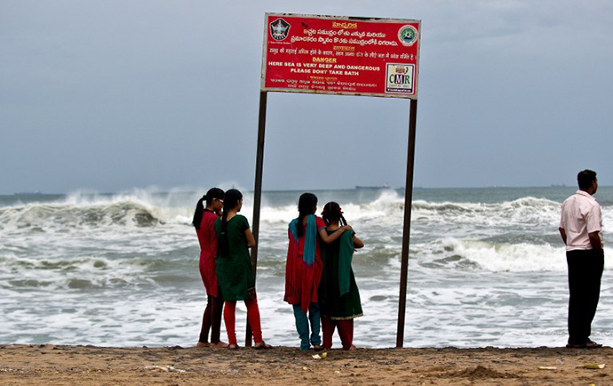 A group of Indian girls watch high tidal waves on the beach in Visakhapatnam on October 12, 2013. (AFP Photo / Manan Vatsyayana)