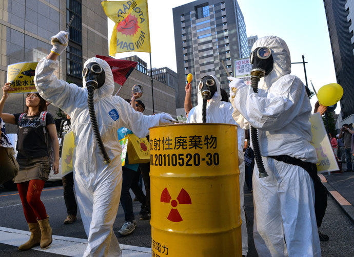 Protestors in radiation protection suits bang a drum can during an anti nuclear demonstration in front of the headquarters of the Tokyo Electric Power Co (TEPCO) in Tokyo on October 13, 2013.(AFP Photo / Yoshikazu Tsuno)