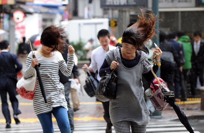 People walk against strong wind and rain in Tokyo on October 16, 2013 (AFP Photo / Yoshikazu Tsuno)