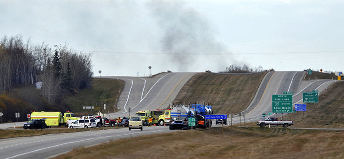 Smoke rises in the distance as firefighters block a highway leading to an area where a train derailed, in the small town of Gainford, Alberta west of Edmonton October 19, 2013. (Reuters / Dan Riedlhuber)