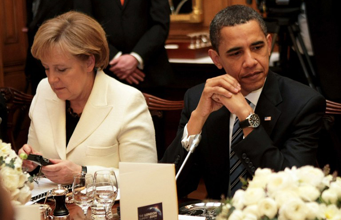 German Chancellor Angela Merkel looking at an electronic device as she sits next to US President Barack Obama (AFP Photo / Christopher Furlong)