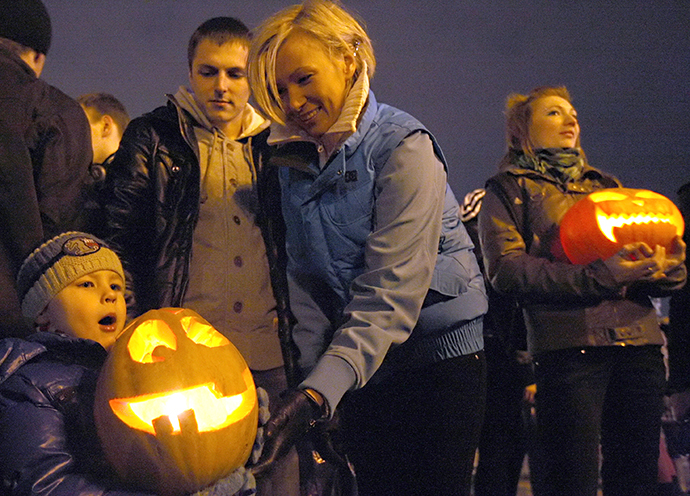 A kid holds a pumpkin during a flashmob marking Halloween celebrations at St. Petersburg's Palace Square. (RIA Novosti / Olga Maltseva)