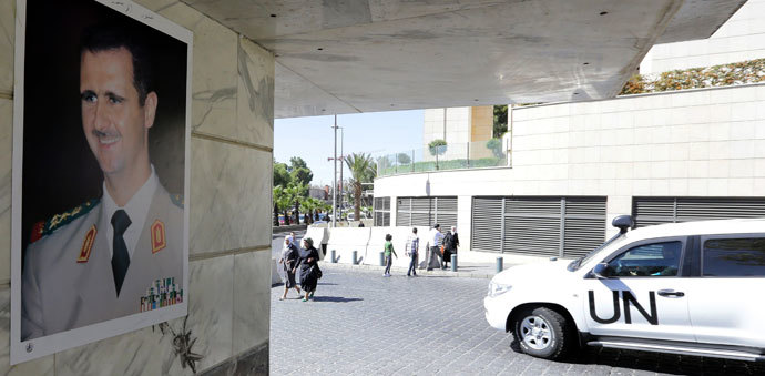 A poster of Syrian President Bashar al-Assad adorns a wall as a United Nations vehicle carrying inspectors from the Organisation for the Prohibition of Chemical Weapons (OPCW) leaves a hotel in Damascus, on October 9, 2013.(AFP Photom / Louai Beshara)