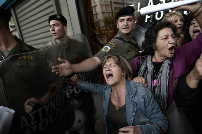 Protesters are pushed back from the riot police as EU and IMF officials escorted out from the emergency exit of the Greek Finance Ministry after their meeting with the Greek Finance Minister in Athens on November 5, 2013. (AFP Photo/Aris Messinis)