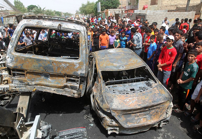 Iraqis gather around burnt vehicles at the site of a car bombing at a market in Baghdad's impoverished district of Sadr City on May 16, 2013 as at least eight people were killed in blasts across the country. (AFP Photo / Ahmad Al-Rubaye)