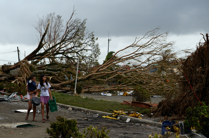 Women walk past fallen trees and destroyed houses in the aftermath of Super Typhoon Haiyan in Tacloban, eastern island of Leyte on November 9, 2013.(AFP Photo / Noel Celis)
