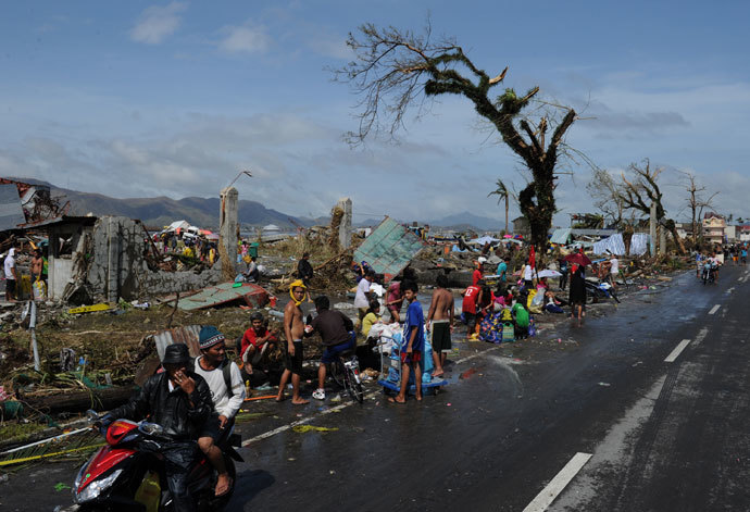 Residents take a bath and wash their belongings next to debris along a road in Tacloban, on the eastern island of Leyte on November 10, 2013 after Super Typhoon Haiyan swept over the Philippines.(AFP Photo / Ted Aljibe)