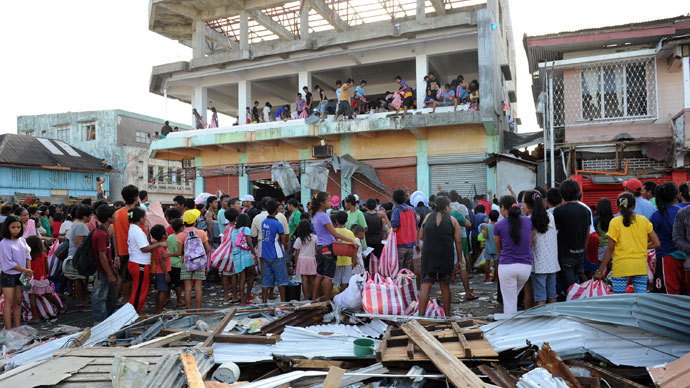 Residents watch as others throw looted goods from a warehouse in the town of Guiuan, Eastern Samar province in the central Philippines on November 11, 2013.(Reuters / Ted Aljibe)