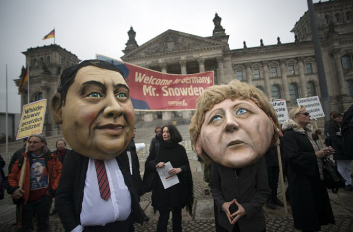 Campact activists wear masks of German Chancellor Angela Merkel (R) and the social democratic SPD party's leader Sigmar Gabriel and hold up a portrait of US whistleblower Edward Snowden in front of the Reichstag building housing the Bundestag (lower house of parliament) in Berlin on November 18, 2013. (AFP Photo / Johannes Eisele)