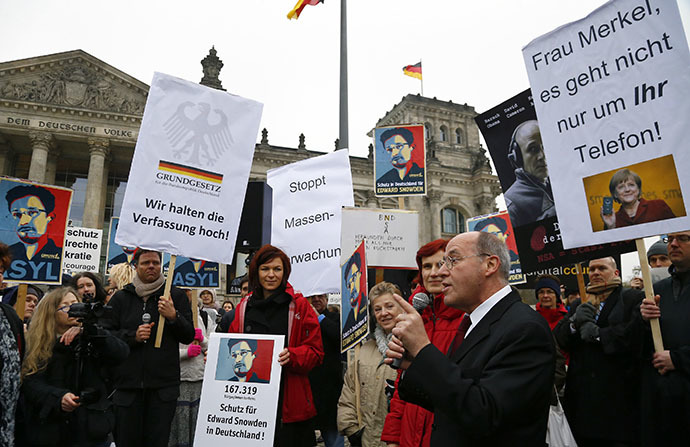 Gregor Gysy of the left-wing party Die Linke (R) addresses demonstrators supporting Edward Snowden, outside the German lower house of parliament Bundestag in Berlin November 18, 2013. The banners read: "Miss Merkel it is not just about your phone", "Safety for Edward Snowden in Germany", "We hold up the constitution".(Reuters / Tobias Schwarz)