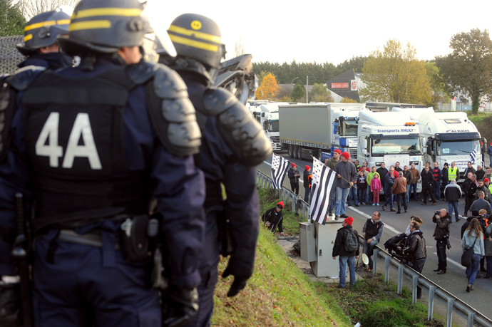 Anti-riot policemen (L) look at truck drivers blocking a part of a highway near Lanrodec, western of France, to protest against an environmental tax on November 16, 2013. (AFP Photo / Fred Tanneau) 