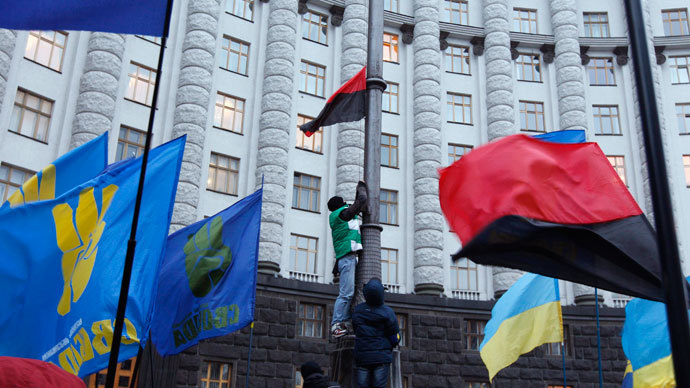 A man attaches a red and black flag, widely used by Ukrainian nationalists, to a lamp post in front of the Ukrainian cabinet of ministers building in the early morning hours during a rally to support EU integration in Kiev December 5, 2013.(Reuters / Vasily Fedosenko)