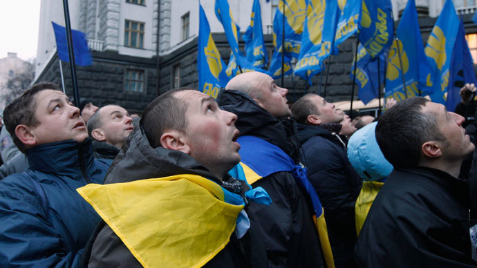 Men look at a flag being attached to a lamp post as they gather in front of the Ukrainian cabinet of ministers building, during a rally to support EU integration in Kiev December 5, 2013.(Reuters / Vasily Fedosenko)
