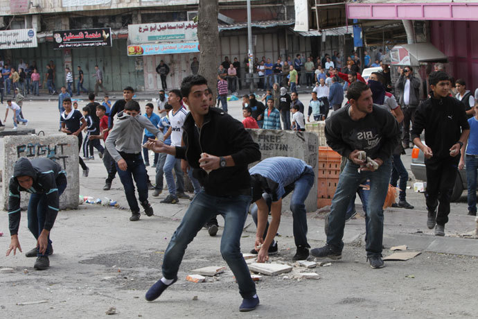 Palestinian stone throwers hurl stones towards Israeli troops during clashes at an Israeli checkpoint in the divided West Bank city of Hebron, near the Jewish settlements of Beit Hadassa and Tal Romeda on September 24, 2013.(AFP Photo / Hazem Bader)