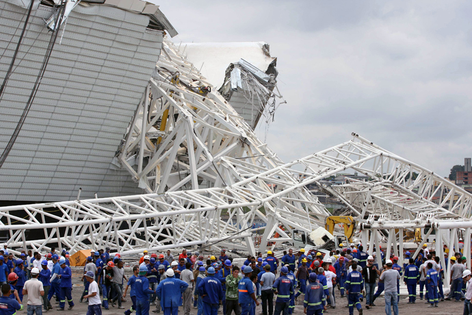 Workers stare at damages after a crane fell across part of the metallic structure at the Arena de Sao Paulo --Itaquerao do Corinthians-- stadium, still under construction, on November 27, 2013 in Sao Paulo. (AFP Photo / Lancepress - Eduardo Viana)