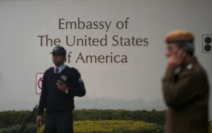 A U.S. embassy security guard (L) and an Indian policeman stand in front of the main gate of the embassy as the bulldozer (unseen) removes the security barriers, in New Delhi December 17, 2013 (Reuters / Adnan Abidi)