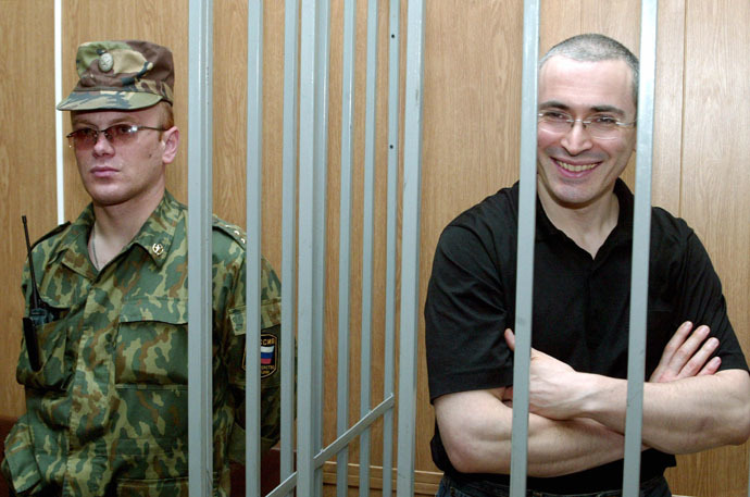 Russian oil magnate Mikhail Khodorkovsky smiles as he stands behind bars during his trial in Moscow, July 16, 2004. (Reuters/Sergei Karpukhin CVI/JV)