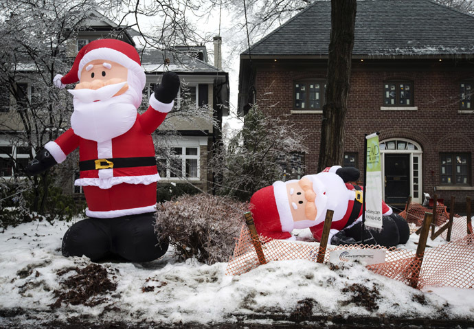 Inflatable Santa Claus decorations, one still inflated and another deflated due to a power outage, are pictured after an ice storm hit Toronto, December 22, 2013. (Reuters/Mathieu Belanger)
