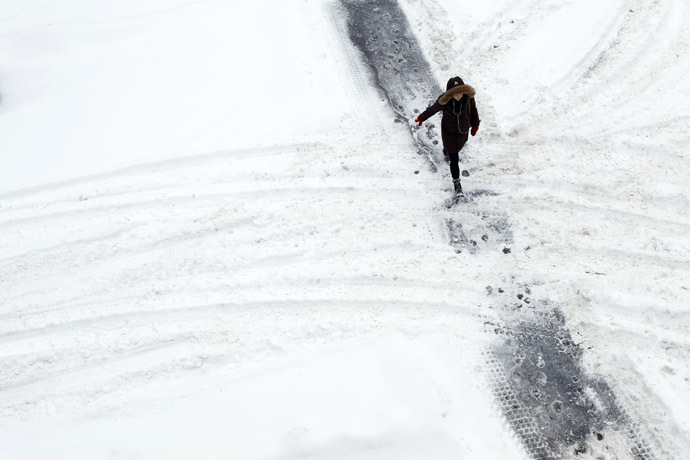 A woman walks along a path cleared in the snow while crossing a street in Ottawa December 22, 2013. (Reuters/Chris Wattie)