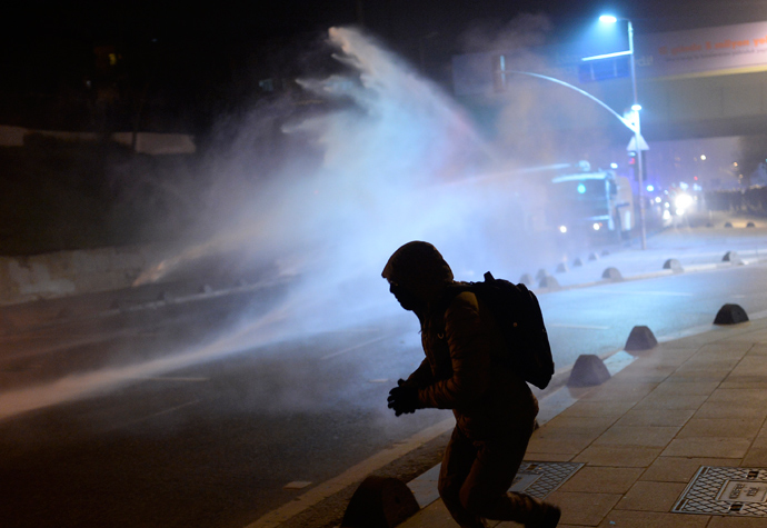 A demonstrator runs away after throwing a projectile toward riot police spraying tear gas during a demonstration against corruption in the Kadikoy district of Istanbul on December 25, 2013 (AFP Photo / Bulent Kilic)