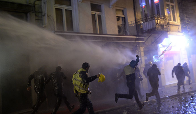 Protesters run from a water cannon on the Istiklal Avenue on December 27, 2013, during clashes between the Turkish police and protestors. (AFP Photo / Bulent Kilic)