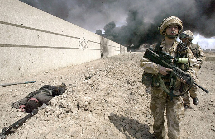 British soldiers walk past a dead fighter around the parameters of Basra technical college, Iraq 03 April 2003. (AFP Photo / Odd Andersen)