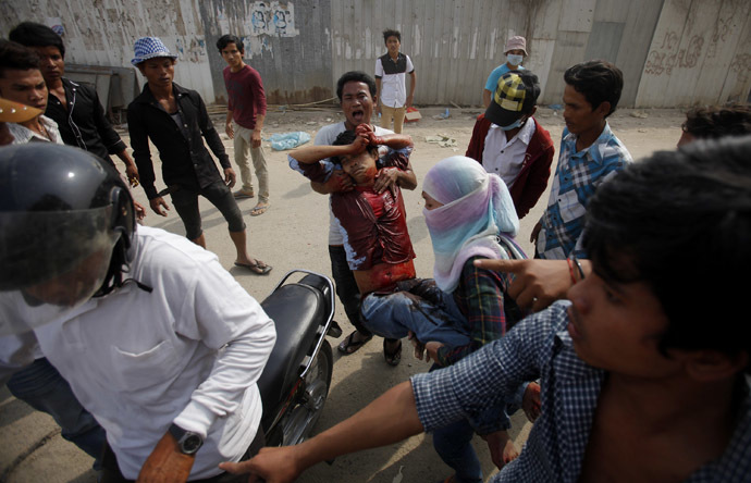An injured garment worker is helped by his colleagues after clashes broke out during a protest in Phnom Penh January 3, 2014. (Reuters/Samrang Pring)