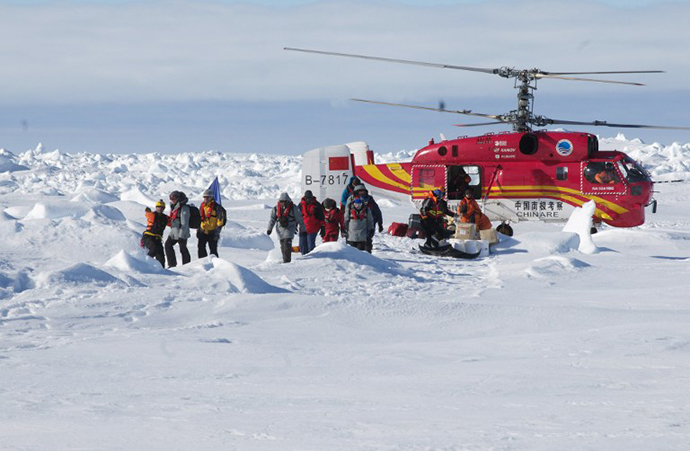 This photo released by the Australian Antarctic Division on January 2, 2014 shows a rescue worker (L) directing passengers who spent Christmas and New Year trapped on the icebound Russian research vessel Akademik Shokalskiy in Antarctica after they disembarked from a rescue helicopter from the Chinese ship Xue Long (R), after they were airlifted from the ice in a dramatic rescue mission. (AFP Photo / Jessica Fitzpatrick)
