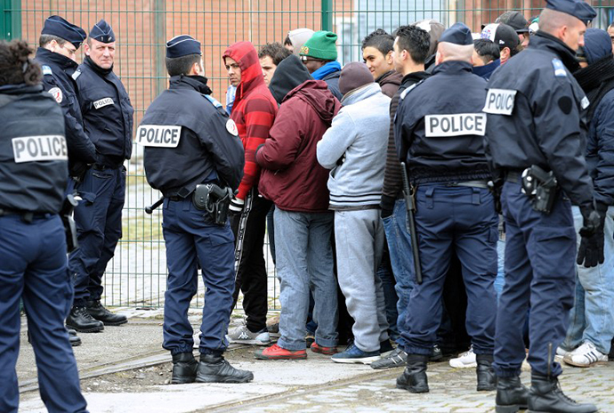 French police watch illigal immigrants wait in line on February 28, 2013 to receive meals from the "La Belle Etoile" (Pretty Star) association in the port of the northwestern French city of Calais. (AFP Photo / Philippe Huguen)