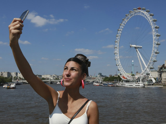 A tourist takes a picture of herself in front of the River Thames and the London Eye in central London (Reuters/Olivia Harris)