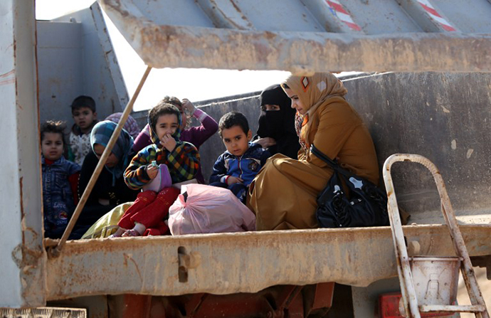 Iraqi women and children, who fled Fallujah, sit in the back of a truck as they wait at an army checkpoint at Ayn al-Tamer crossing at the entrance to Karbala province on January 6, 2014. (AFP Photo / Ahmad Al-Rubaye)