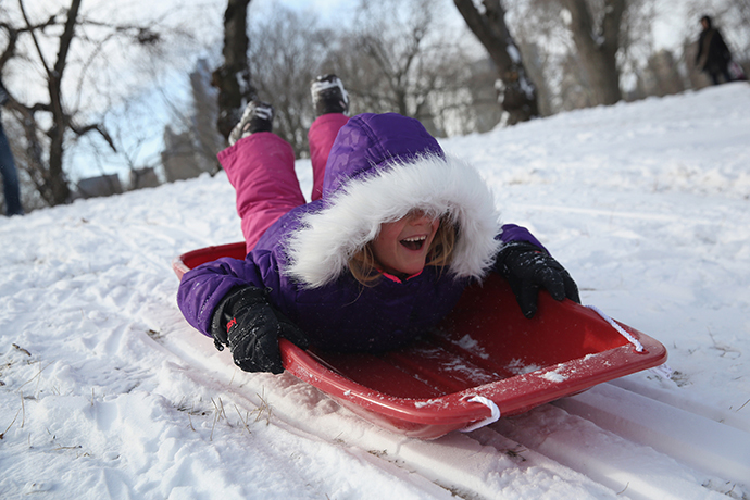 A young girl sleds down a hill in Central Park after a winter storm on January 3, 2014 in New York, United States. (AFP Photo / Getty Images / John Moore)