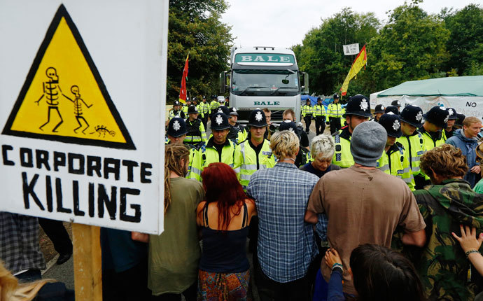 Demonstrators stand in the road as police escort a lorry to the entrance of a drilling site run by Cuadrilla Resources, in the village of Balcombe in southern England September 3, 2013.(Reuters / Luke MacGregor)