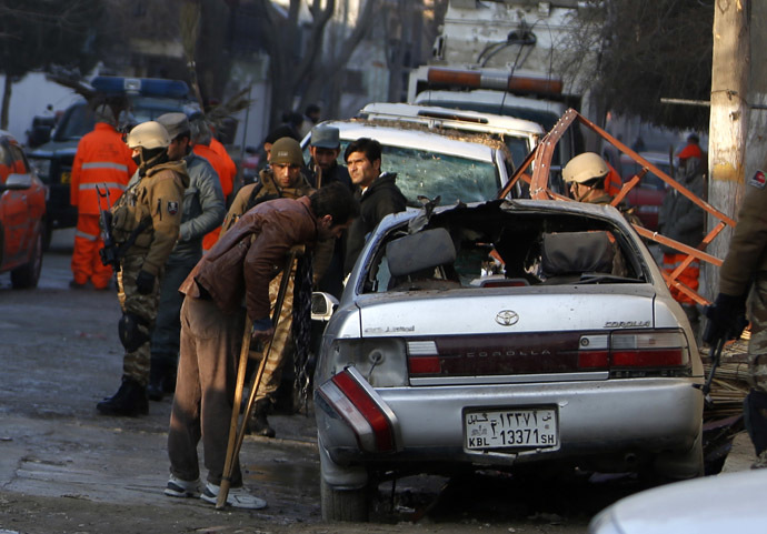 Fawad, a worker of a Lebanese restaurant who was injured during a suicide bombing attack outside the restaurant, looks at a damaged vehicle near the restaurant in Kabul January 18, 2014. (Reuters/Mohammad Ismail)