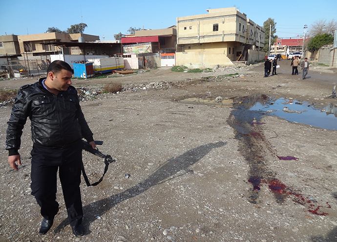 A member of Iraqi security forces inspects the site of a bomb explosion in the northern Iraqi city of Kirkuk on January 18, 2014. (AFP Photo / Marwan Ibrahim)