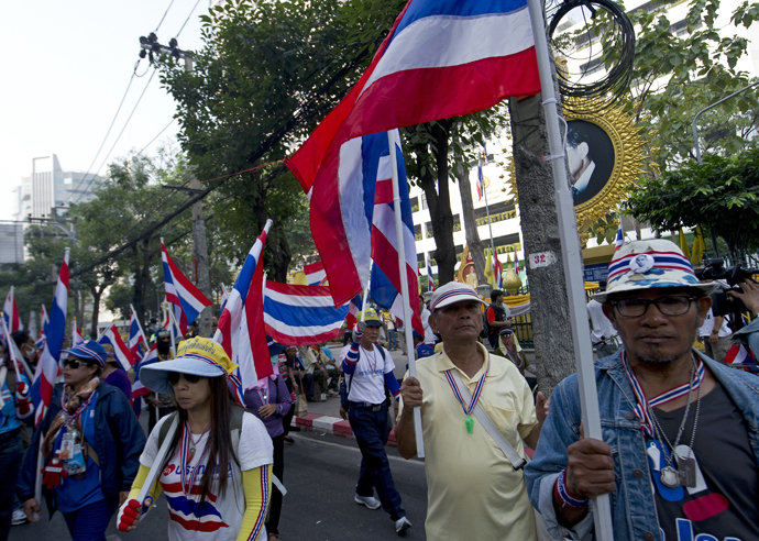 Thai anti-government protesters hold national flags as they parade to surrounded polling stations during a rally in Bangkok on January 26, 2014 (AFP Photo)