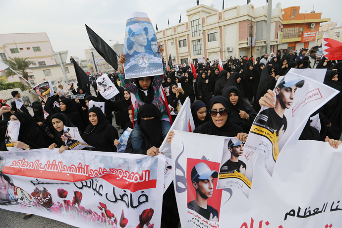 Anti-government protesters holding photos of Fadhel Abas Muslim, shout anti-government slogans as they march during his funeral in the village of Diraz west of Manama, January 26, 2014. (Reuters/Hamad I Mohammed)