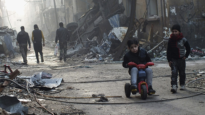 A boy rides on a tricycle along a damaged street in the besieged area of Homs (Reuters / Yazan Homsy)
