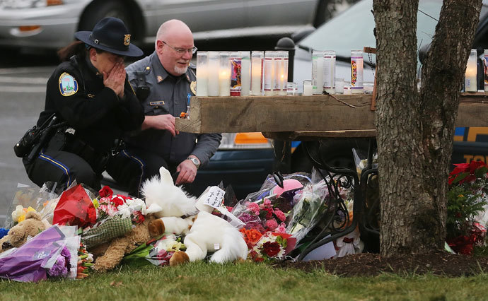Newtown Police officers pay their respects at a makeshift memorial outside St. Rose of Lima Roman Catholic Church during the first day of Sunday services following the mass shooting at Sandy Hook Elementary School on December 16, 2012 in Newtown, Connecticut.(AFP Photo / Mario Tama)