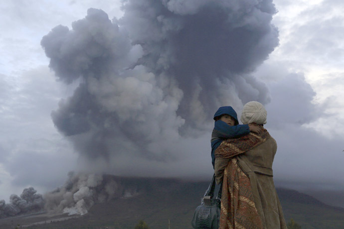 A mother holds her son as they watch the eruption of Mount Sinabung at Berastepu village in Karo district, Indonesia's North Sumatra province, January 10, 2014. (Reuters)
