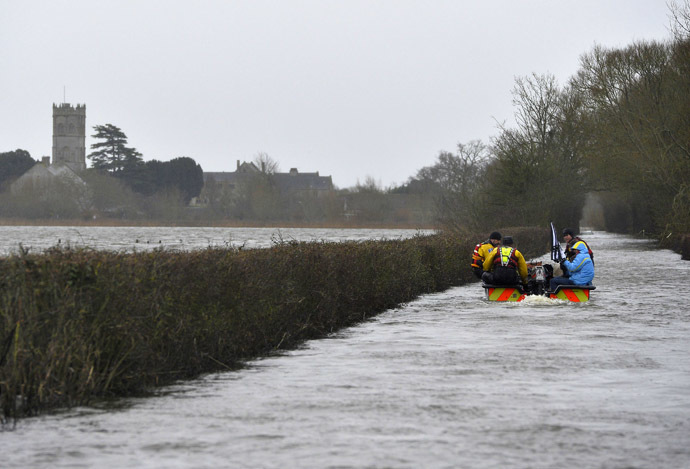 A boat operated by emergency services personnel carries local residents along a flooded road from the village of Muchelney on the Somerset Levels, near Langport in south west England January 31, 2014. (Reuters/Toby Melville)
