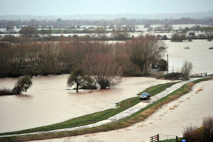 A car is driven on a road surrounded by flooded fields near Curload in Somerset, southwest England, on February 1, 2014. (AFP Photo/Carl Court)