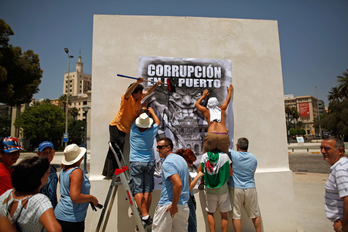 Protesters and members of the Andalusian Union of Workers (SAT) place a banner reading "Corruption at the port" on the wall of a monument at Malaga's port during a demonstration against Spain's unemployment and the corruption in Malaga, southern Spain (Reuters / Jon Nazca)