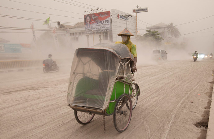A man wears a mask as he rides a becak, a kind of rickshaw, on a road covered with from Mount Kelud, in Yogyakarta February 14, 2014. (Reuters / Dwi Oblo)