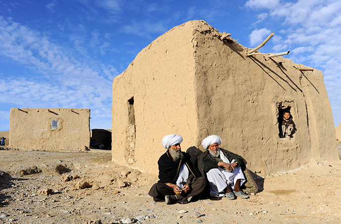 Afghan residents sit outside a hut on the outskirts of Herat on February 12, 2014. (AFP Photo / Aref Karimi)