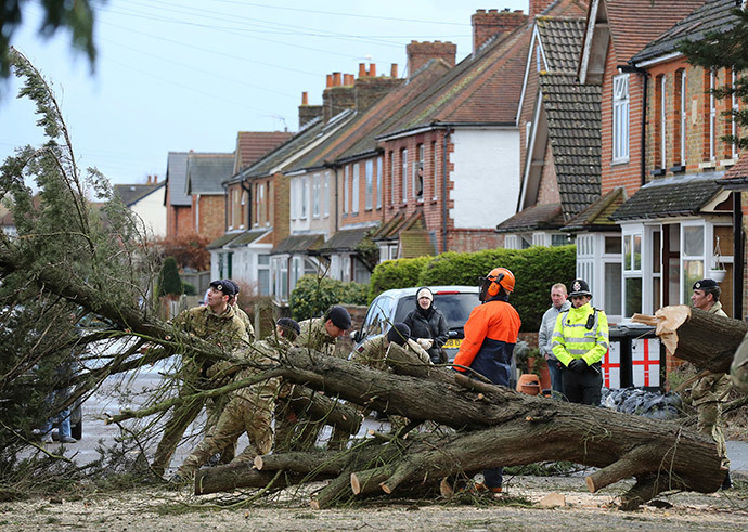 Members of the Army move a tree which was blown down in a flooded street in Egham, southern England, February 15, 2014. (Reuters / Paul Hackett) 