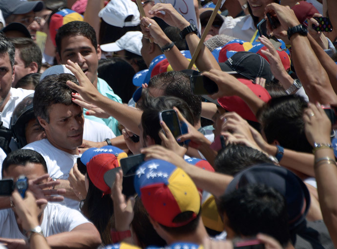 Leopoldo Lopez (L), an ardent opponent of Venezuela's socialist government facing an arrest warrant after President Nicolas Maduro ordered his arrest on charges of homicide and inciting violence, is surrounded by supporters during a demonstration before turning himself in to authorities, in Caracas, on February 18, 2014. (AFP Photo / Raul Arboleda) 
