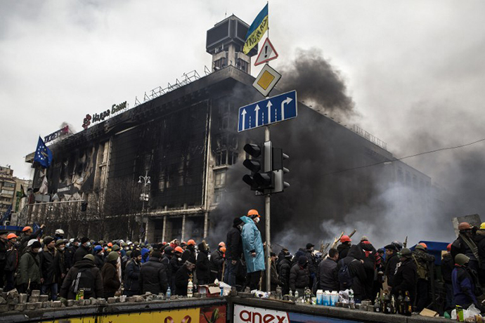 An anti-government rioters stand on February 19, 2014 outside the remains of the Trade Union building on Kiev's Independence Square during clashes with riot police. (AFP Photo / Sandro Maddalena)