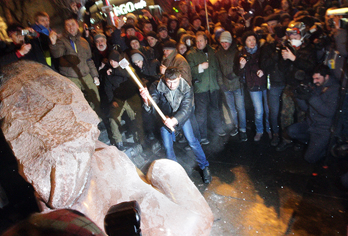 A protester breaks apart a statue of Lenin at a monument in his honor after it was pulled down during a mass rally called "The March of a Million" in Kiev's Independence Square on December 8, 2013. (AFP Photo / Anatoli Boiko)